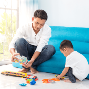 A recently divorced father playing blocks with his son on the floor of their living room