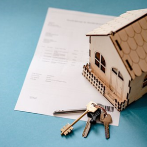 Small wooden toy house and set of house keys sitting on top of paperwork for a property to show if its possible to add a name my property, conveyancing team, solicitors for conveyancing, quality conveyancing, transfer of equity