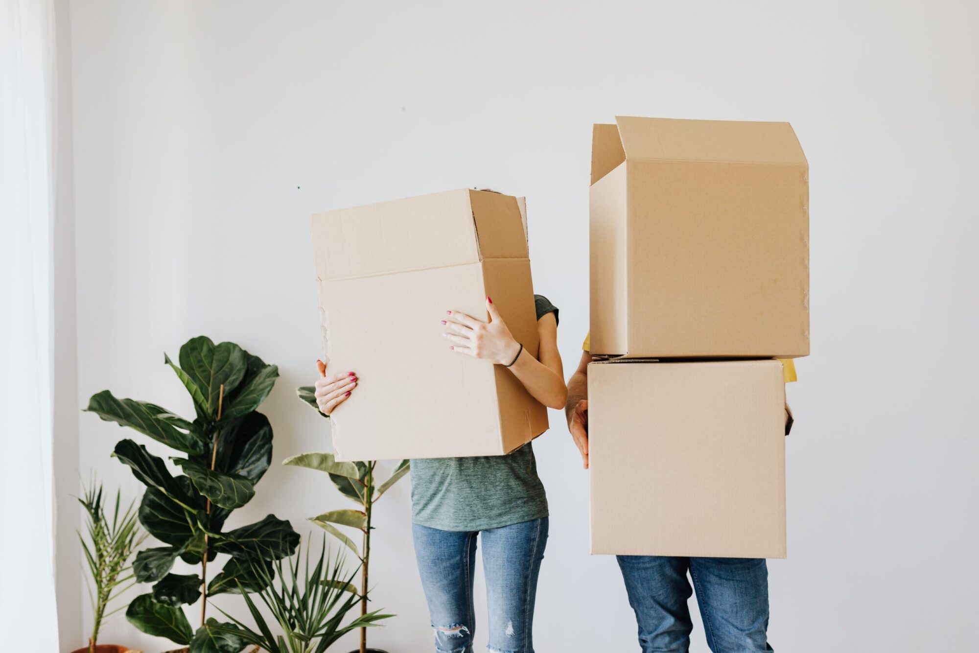 A man and woman holding cardboard boxes getting ready to move house as the house prices fall in 2023